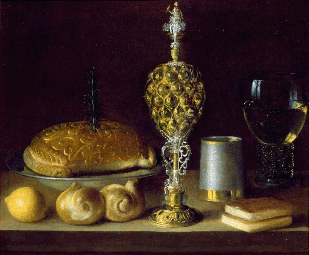 Una natura morta di beverini, una tazza di ananas, un limone, pane e due piccoli libri